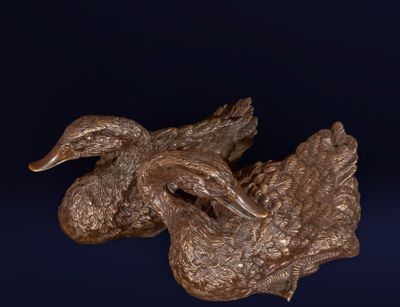 sculpture en bronze représentant un canard perché sur une branche, sur fond bleu