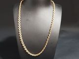 a gold chain necklace on a mannequin with a black background