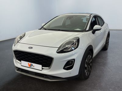 Une voiture blanche est garée dans une pièce au sol noir.