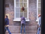 people walking on the sidewalk in front of a brick building