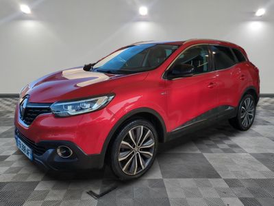 une voiture rouge est garée dans une pièce au sol en damier
