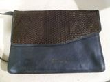 un sac à main marron et noir posé sur une table blanche, muni d'une bandoulière noire