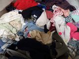 a pile of clothes that is sitting on a bed