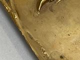 a gold plate with a bird on it on a table