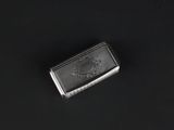 silver cigarette case on a black surface with a black background