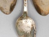 three silver spoons and two silver spoons on a white surface