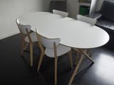 une table blanche avec quatre chaises et un canapé noir en arrière-plan