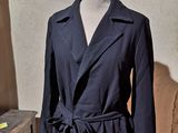 a coat on a mannequin stand in front of a wall