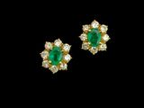 une paire de boucles d'oreilles en émeraude et diamant sur fond noir