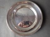 a silver plate on a table with a reflection of a person in it