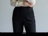 woman wearing a white shirt and black pants with a gold bracelet