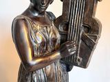 bronze statue of a woman holding a harp on a marble base