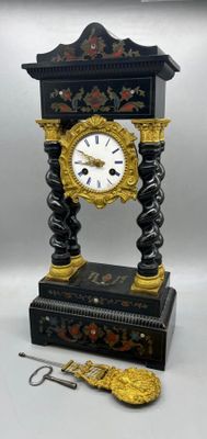 a black and gold clock sitting on top of a table next to a pair of scissors