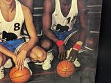 two men sitting on a basketball court holding basketballs