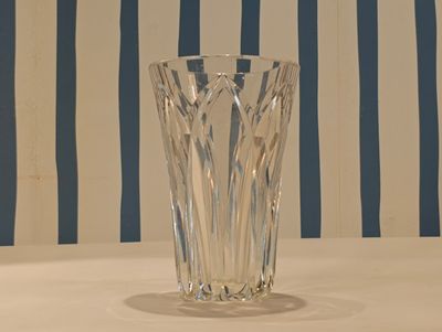 a glass vase sitting on a table with a striped wall behind it