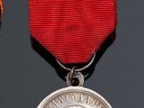 an image of a silver medal with a red ribbon around it