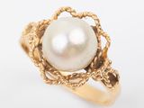 a close up of a gold ring with a pearl in the center