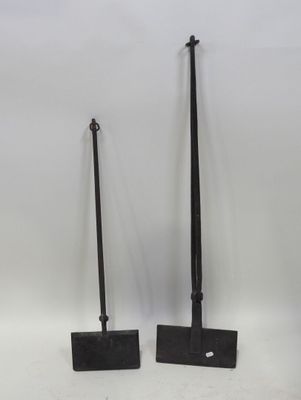 une paire de pelles en fer noir posées sur une surface blanche