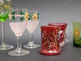 four glasses and a pitcher sitting next to each other on a table