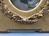 a gold frame with a picture of a young girl in it