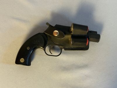 un pistolet noir posé sur une surface blanche, avec une lumière rouge