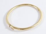 a close up of a gold bang bracelet with a single diamond