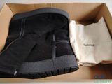 des bottes noires dans une boîte, avec un sac blanc et une paire de bottes noires