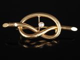 une broche en or ornée d'une perle au centre