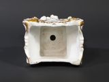 a white and gold vase sitting on a black surface