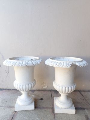 two white vases sitting on the ground next to each other
