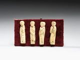 trois figurines en ivoire représentant un homme et une femme, posées sur du velours rouge