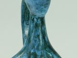 un vase bleu surmonté d'une lampe, à côté d'une paire de boucles d'oreilles