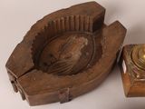 a wooden ashtray and a brass ashtray on a table