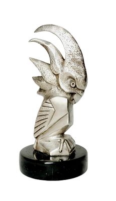 statue représentant un oiseau sur un socle noir, avec un fond blanc