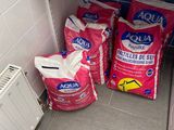 three bags of cat food sitting on the floor next to a refrigerator
