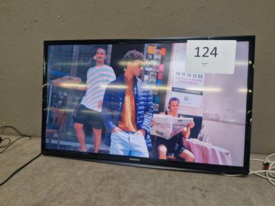 a flat screen tv sitting on a table with a couple of people in the background