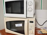 two microwaves sitting on top of a wooden counter