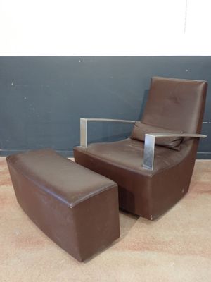a chair and ottoman in a room with a wall in the background