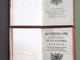 un livre ouvert posé sur une table noire, près d'un mur vert