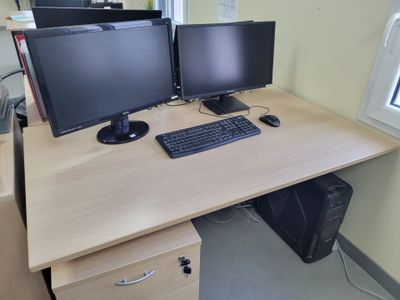 two computer monitors sitting on top of a wooden desk