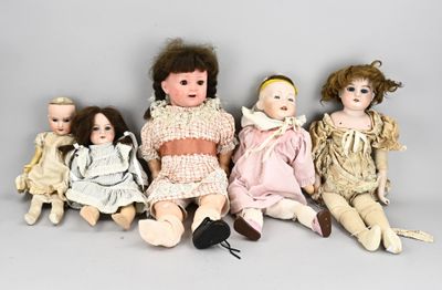 several antique dolls are lined up in a row on a gray surface