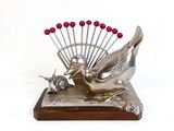 une sculpture en argent représentant un oiseau et un éventail posée sur une table