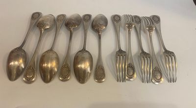 six spoons and six forks are lined up on a table