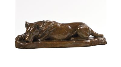 une statue en bronze représentant un chien couché sur un rocher