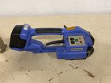 a blue electric tool sitting on the floor next to a piece of wood