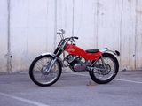a red motorcycle parked in a parking lot next to a white wall