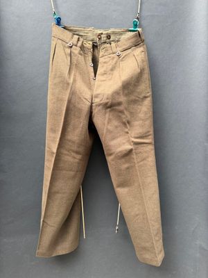 un pantalon beige suspendu à une corde à linge