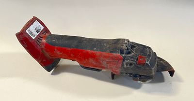 un vieil outil rouge et noir posé sur une surface blanche