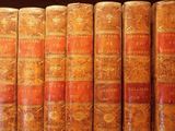 several old books are lined up on a shelf in a library