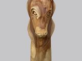 une sculpture en bois représentant une tête de lion sur fond gris